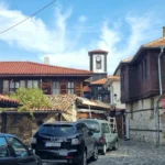 a cobblestone street with a clock tower in the background