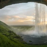 waterfalls near cave at daytime